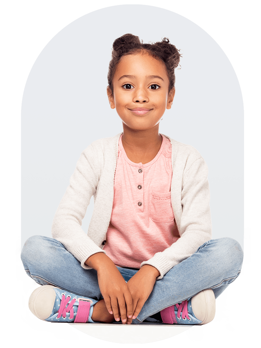Child with a smile sits on the floor with crossed legs
